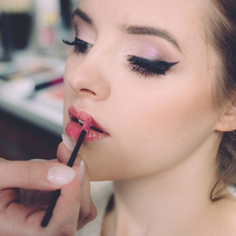 Close-up of an elegant woman having makeup applied, highlighting fashion and beauty.