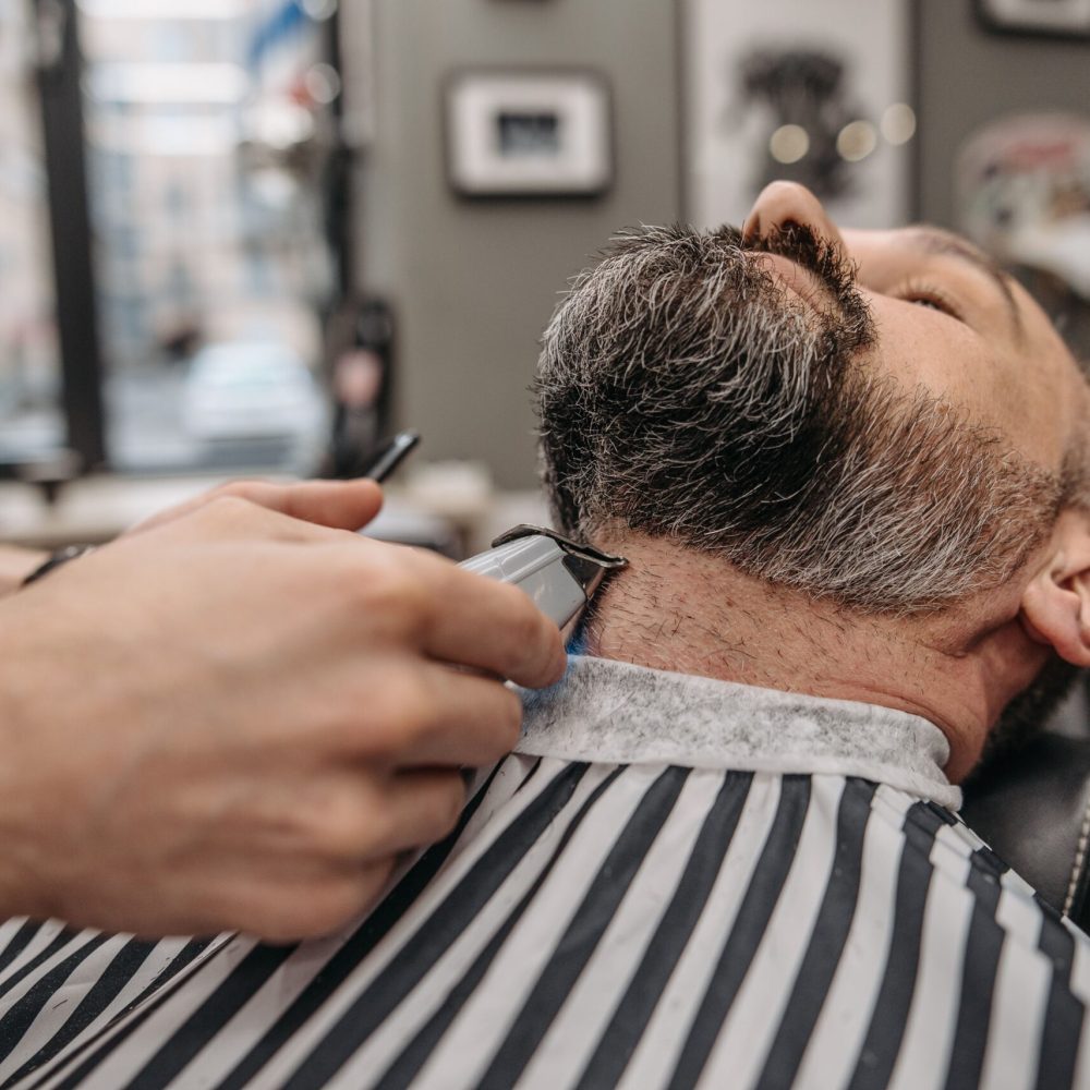 Close-up of a professional barber trimming a man's beard in a stylish barbershop.